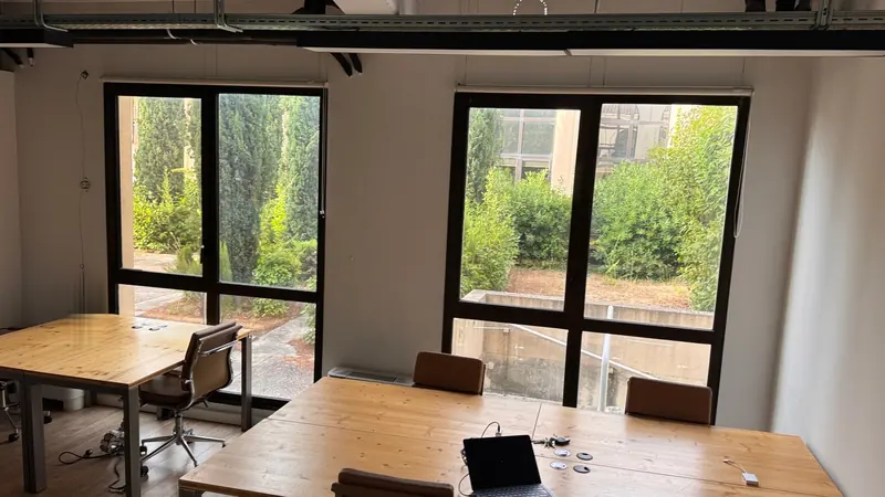 Postes de travail face aux baies vitrées ouvertes sur la verdure