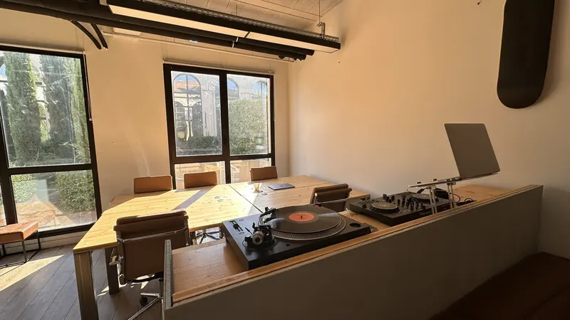 Vue d'ensemble de l'open space au soleil, grande table en bois et baies vitrées